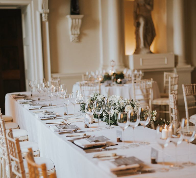 Simple and minimal white wedding tablescape with grey and white stationery and decorative foliage with white flowers 