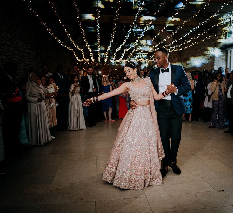 Bride and Groom do first dance at rustic venue, Caswell House. Bride wears a bridal length and groom wears a navy suit