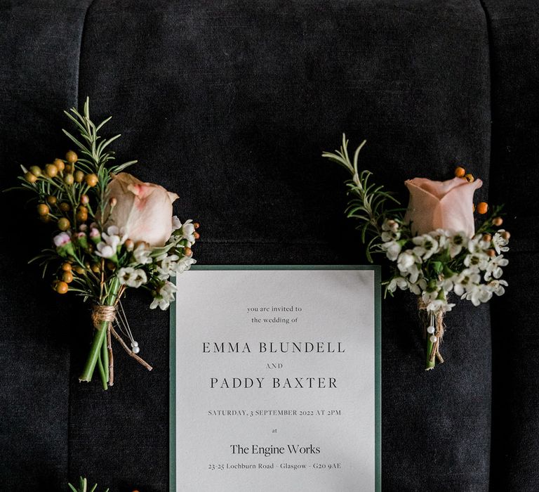 Floral buttonholes tied with brown string beside white stationery 