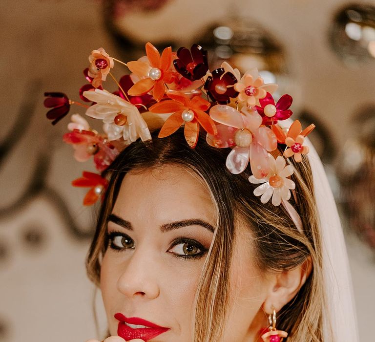 Bride with grunge smokey eye makeup, bold red lip, pink bridal flower crown and pink earrings 