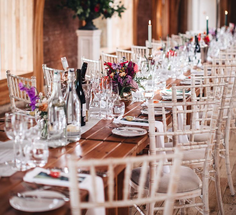 Romantic wedding tablescape with dark green candles in gold candle holders and pink and purple wedding flower arrangement decor 