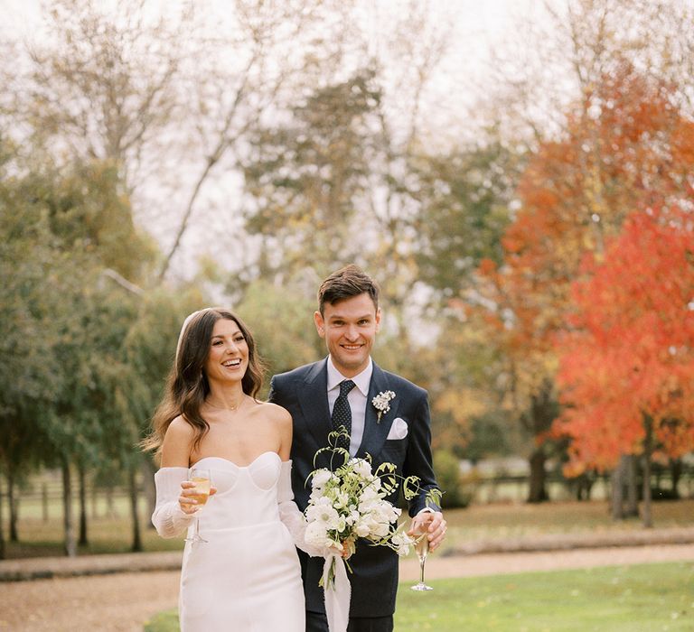 Bride in platform Jimmy Choo pearl shoes wearing a white wedding dress with a split walking with the groom in a navy suit 