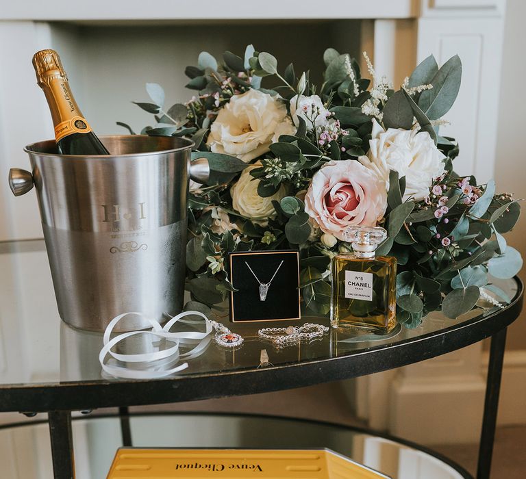 Champagne in personalised champagne ice bucket with the pink and white rose bridal bouquet, bridal jewellery, and bridal Chanel perfume 