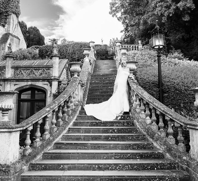 Bride in strapless mermaid Pronovias wedding dress standing on the stairs with statement veil 