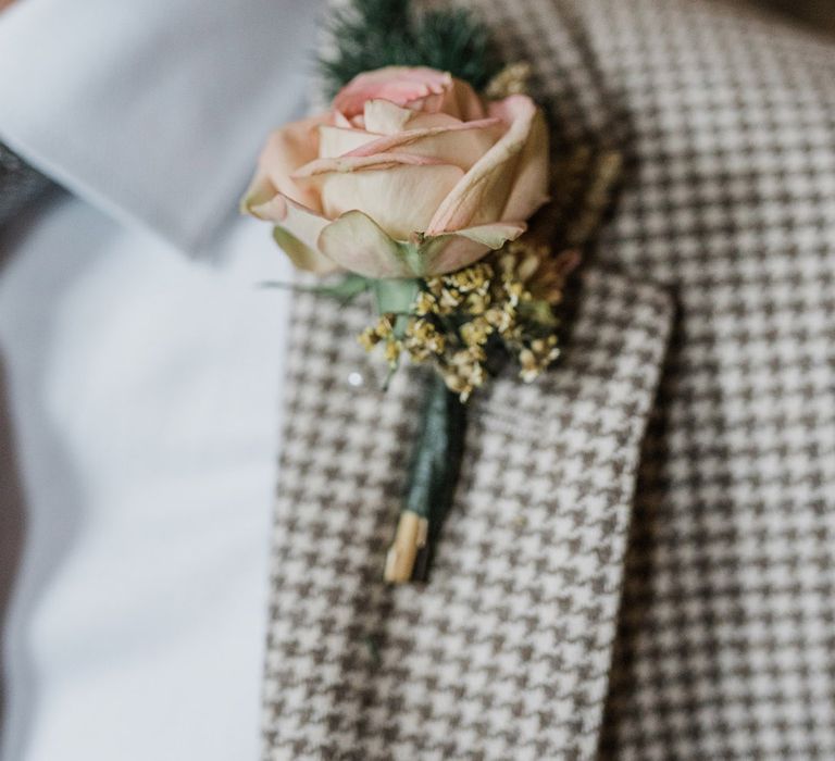 Simple pink rose buttonhole worn by the groom on houndstooth wedding suit 