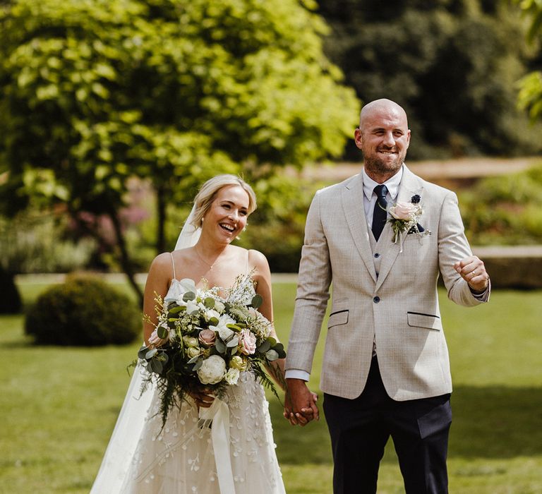 Bride in appliqué wedding dress standing with the groom after their ceremony 