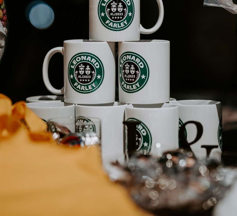 Wedding merch inspiration - Starbucks style mugs with the grooms' surnames on a wedding merch table 