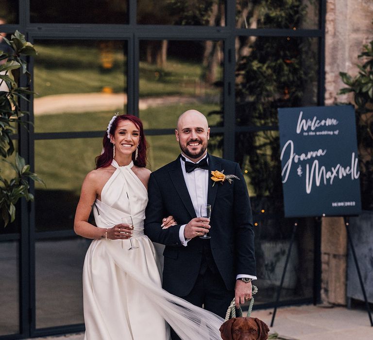 The bride and groom posing with their chocolate brown pet dog 