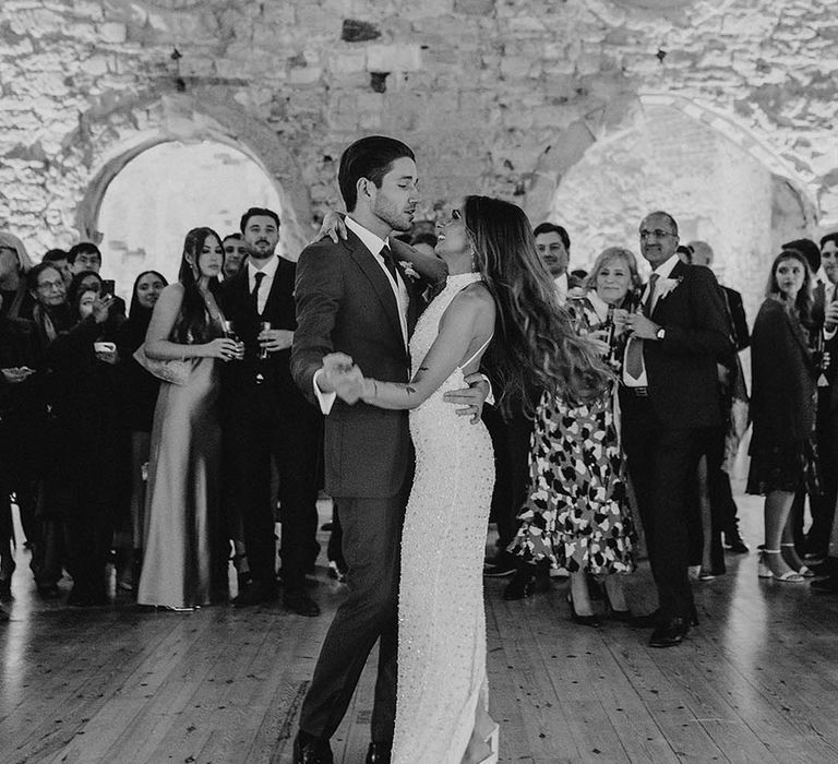 The groom sings to the bride in a halter neck sparkly wedding reception dress for their first dance together 