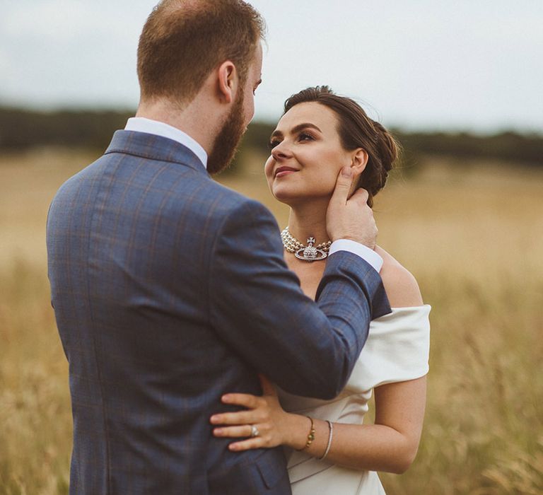 Statement Vivienne Westwood pearl choker worn by the bride with the groom in a dark blue checkered suit 