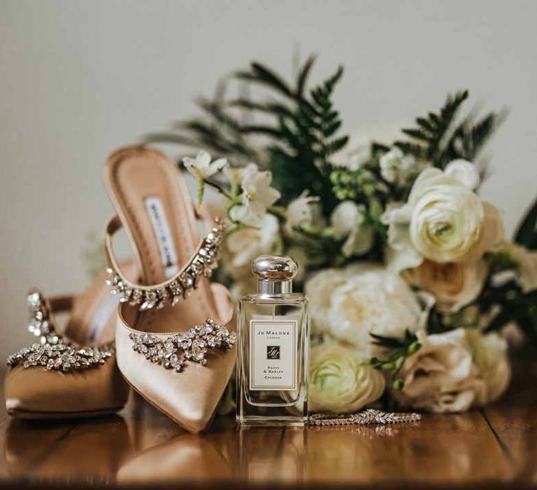 Jo Malone London wedding scent next to light pink bejewelled closed toe wedding heels, silver wedding jewellery and white garden rose, white hydrangea, cows parsley and foliage bridal bouquet 