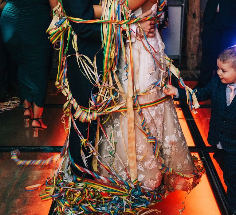 Bride and groom wrapped up in rainbow streamers during wedding first dance at South Farm wedding venue 