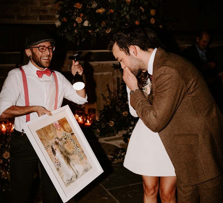 Bride in long sleeve short wedding dress and red velvet chunky wedding heels and groom in brown grooms suit reacting to live wedding painting 