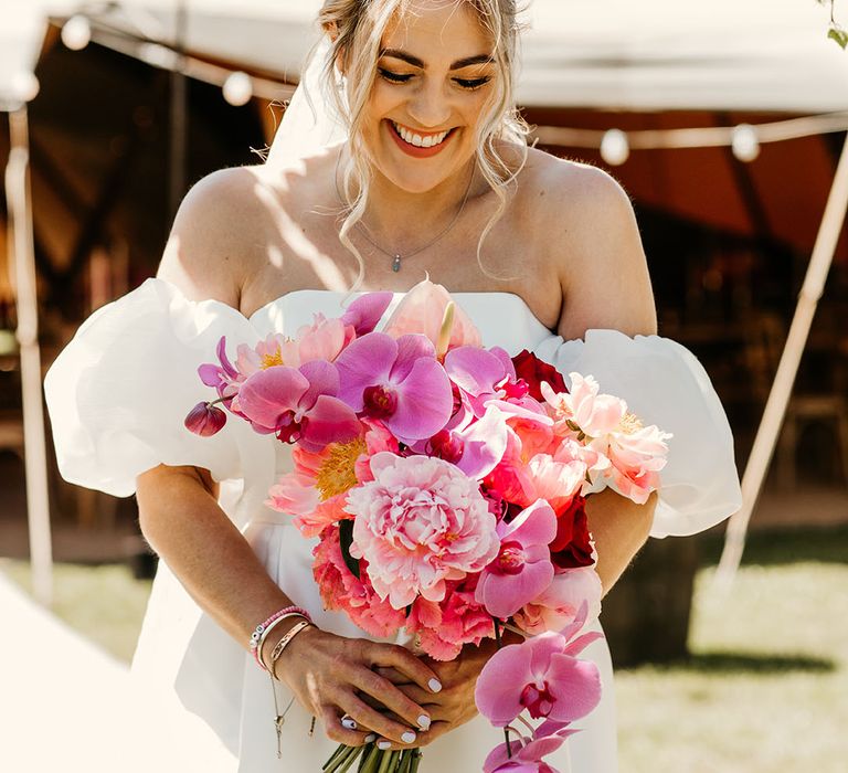 Laughing bride holding bright pink bouquet with orchids and roses 