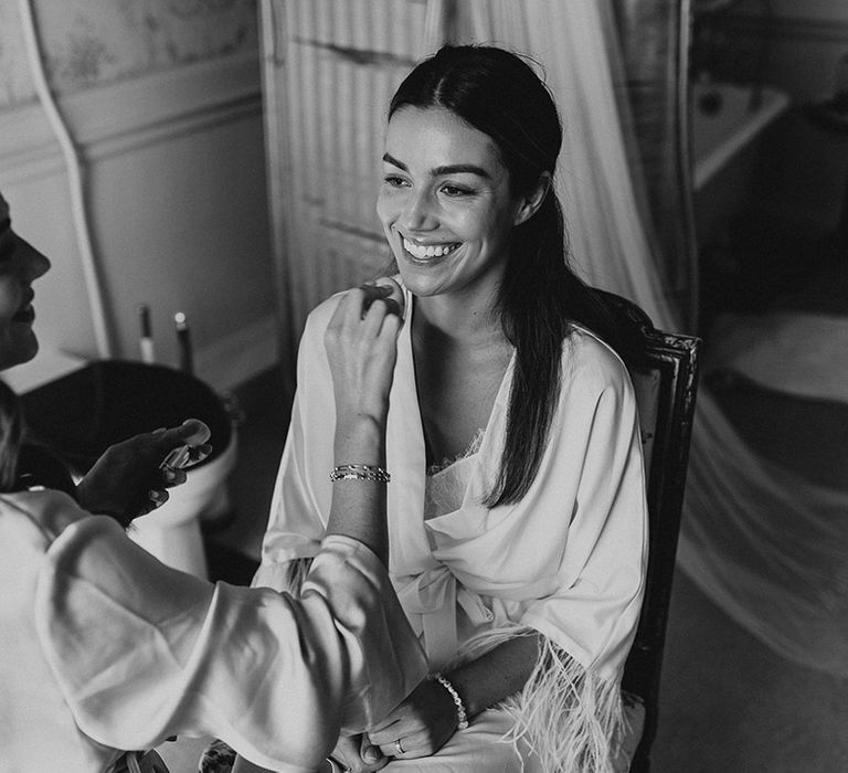 Bride in white robe gets her hair and makeup done for the wedding day at Came House wedding venue