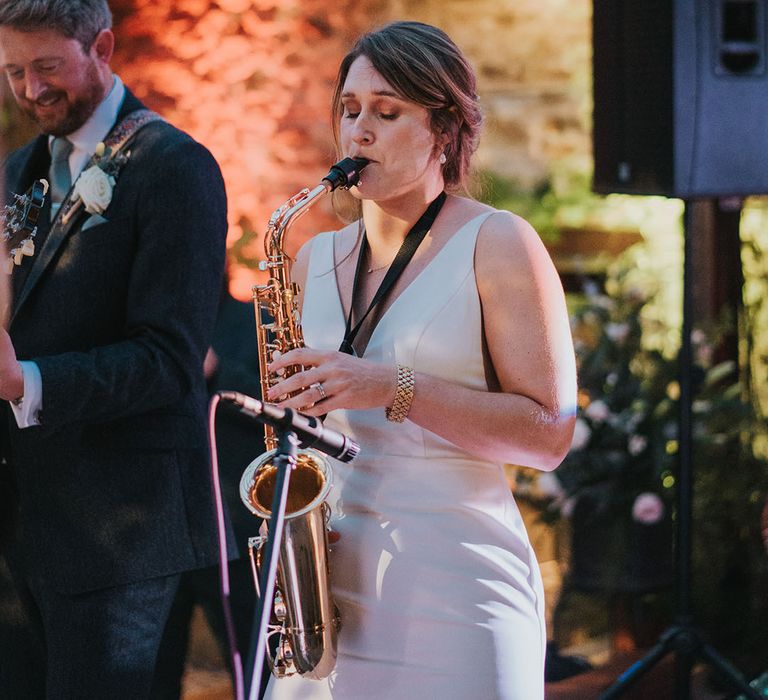 The bride plays a saxophone with the groom playing next to her in his band 