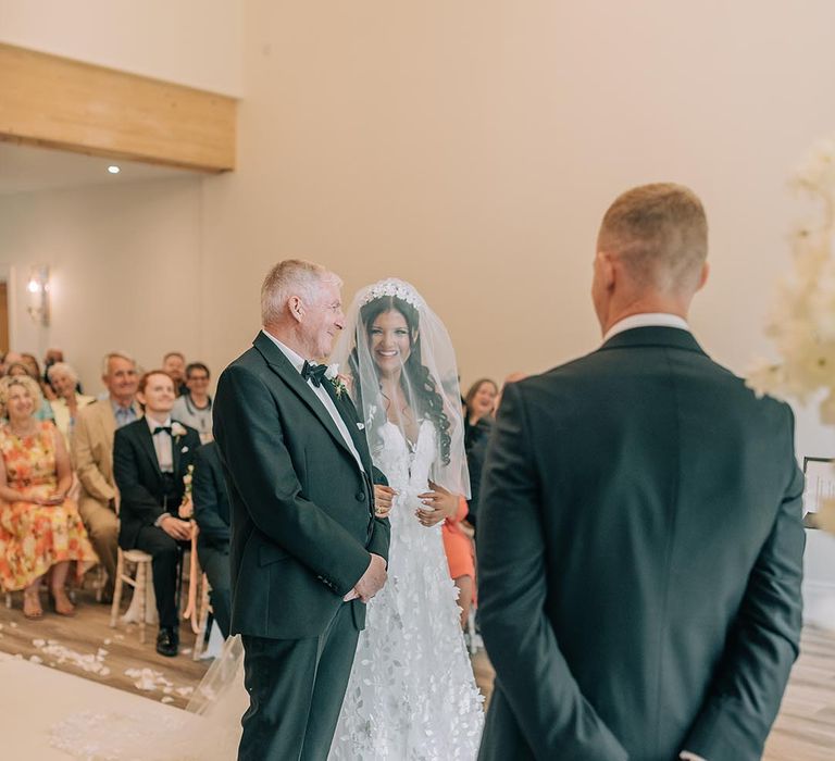 The bride and father of the bride meet the groom at the end of the aisle 