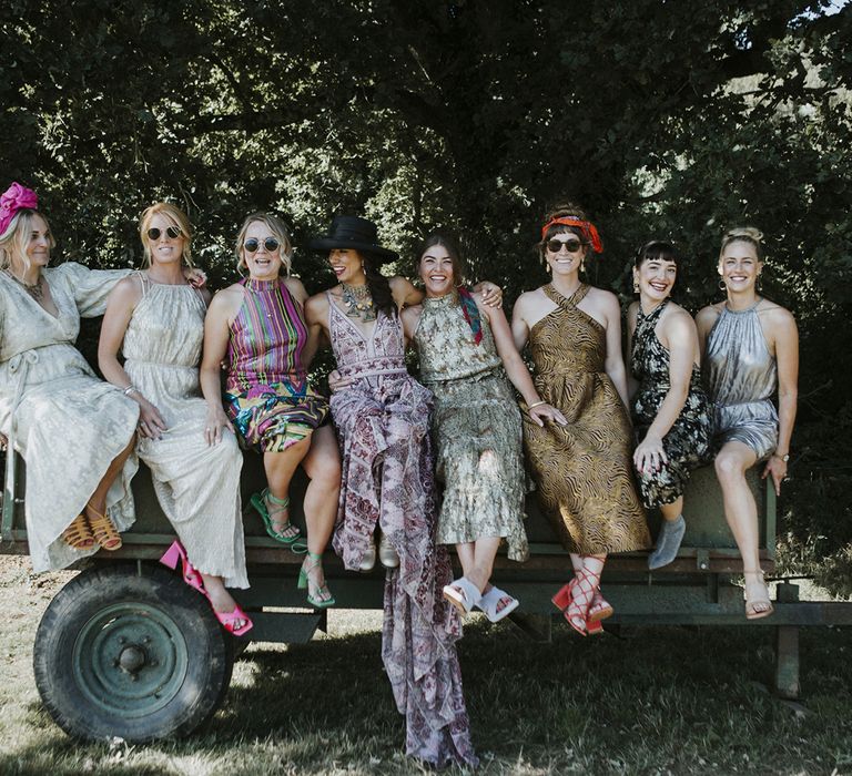 Bride in pink boho wedidng dress sits with friends in woodlands at tipi wedding