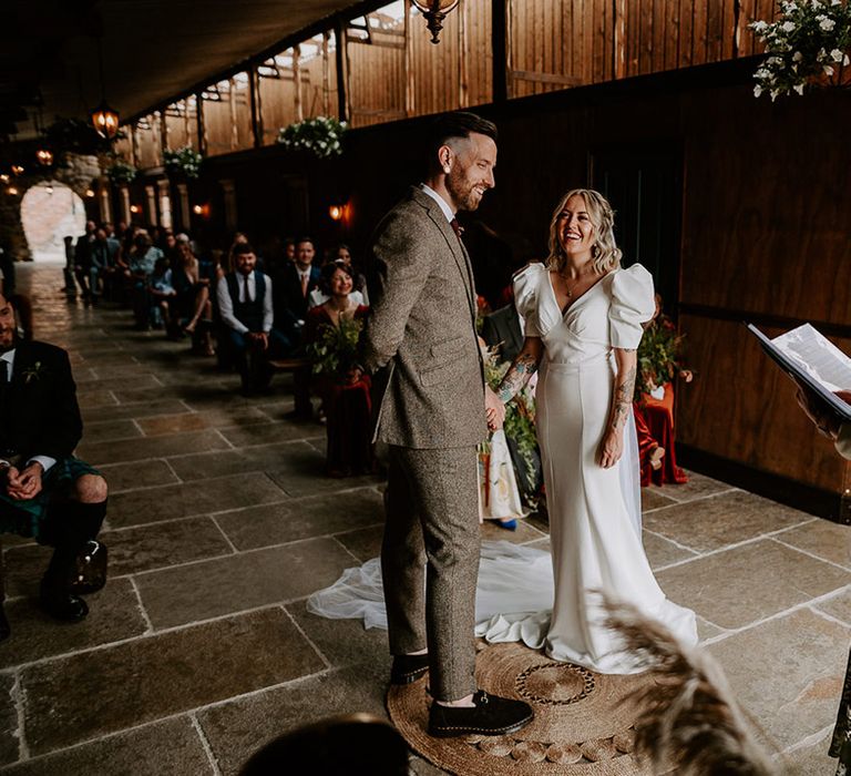 Bride in puff sleeve wedding dress with the groom in a grey tweed suit 