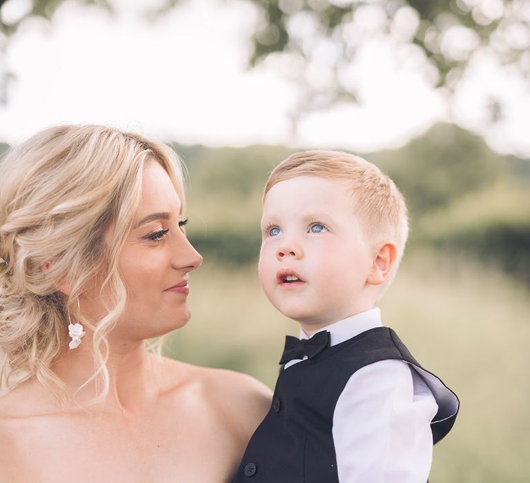 Bride in strapless wedding dress holding her son page boy