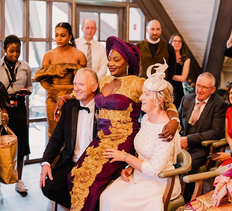 Bride wearing luxe purple and gold wedding outfit with the mother and father of the bride 