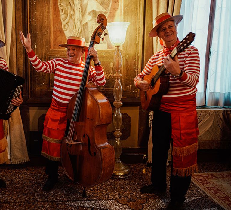 Venice hotel wedding with band in red and white striped outfits playing instruments 