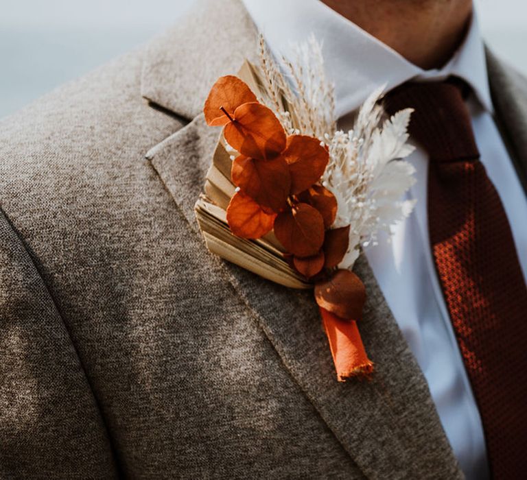 Close up of the dried flower boho buttonholes for the groom on a grey suit jacket 