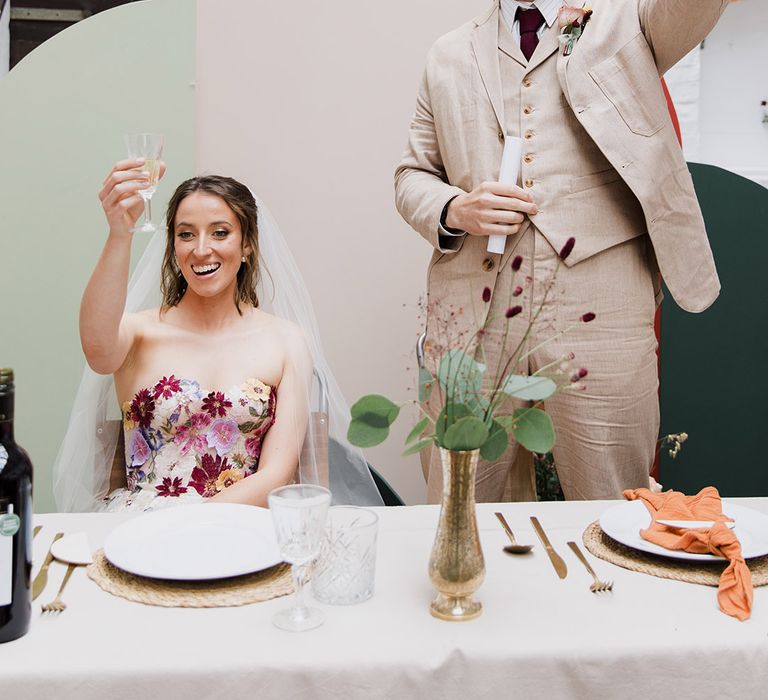 Groom in light beige suits makes a wedding speech and raises a toast to the bride 