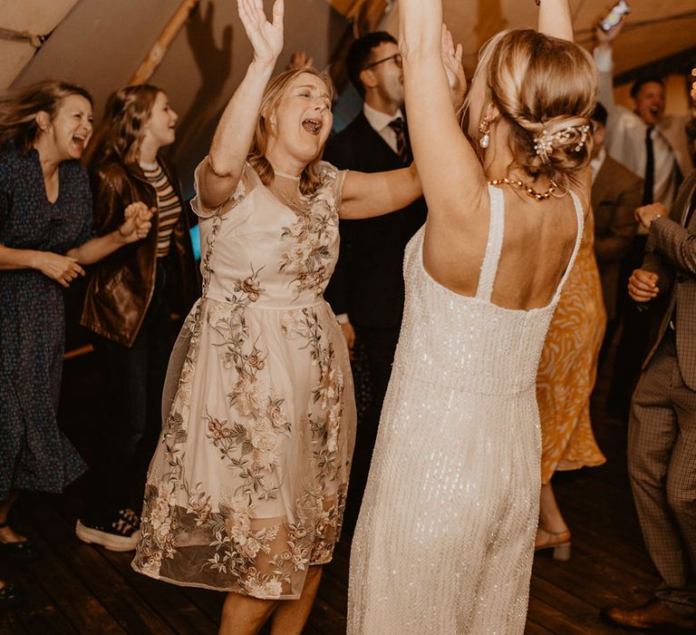 Bride dancing with mother and wedding guests at wedding reception 