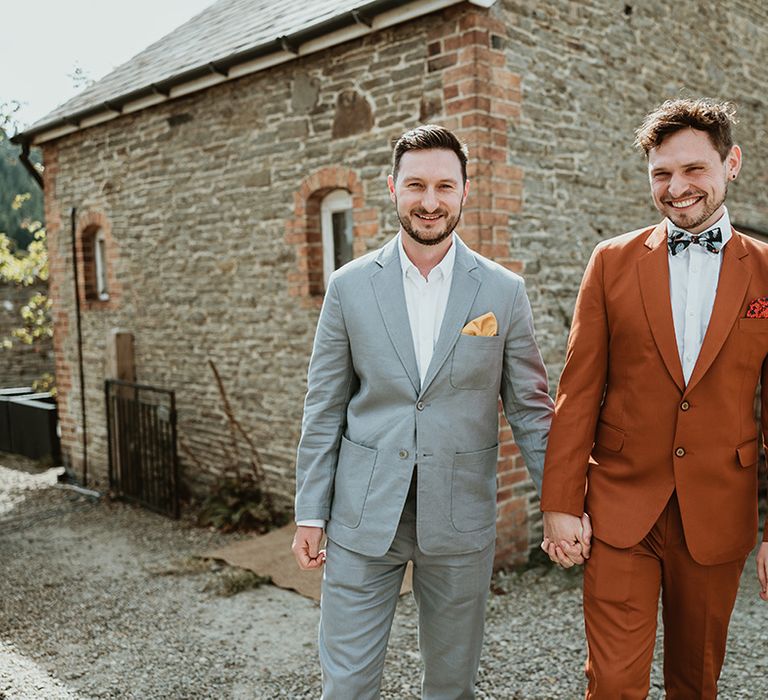 First look moment for same sex gay couple in grey and orange wedding suits 