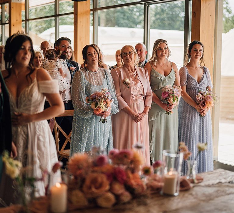 The bridesmaids wearing pastel mismatched bridesmaid dresses for summer wedding 