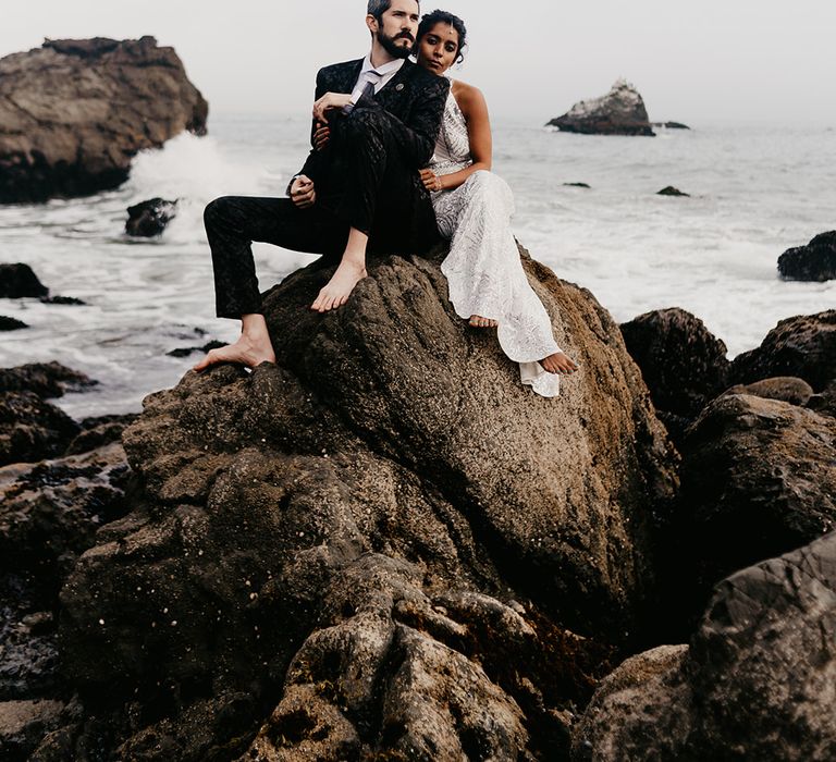 Stylish bride and groom sitting on the rocks 