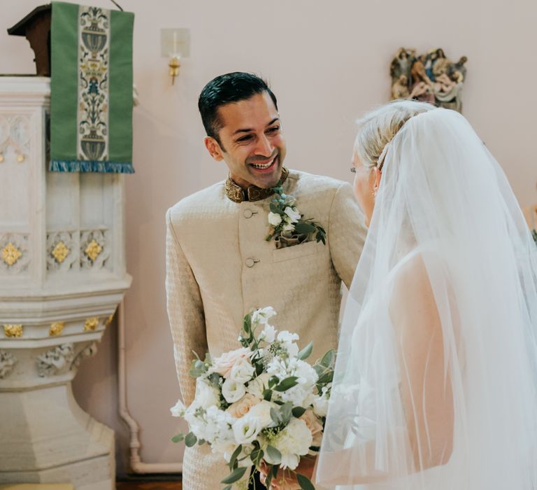 Groom in bespoke suit smiling at his bride 