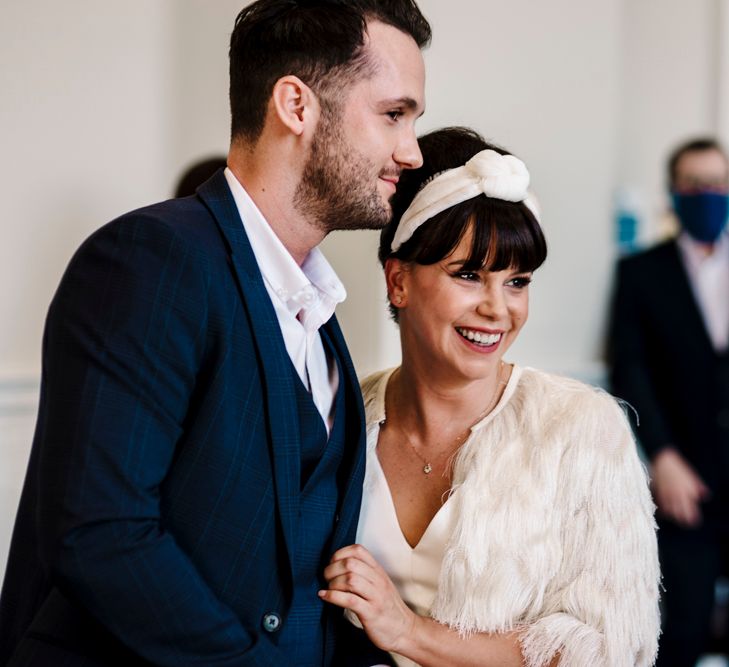 Bride and groom smiling during intimate registry office wedding ceremony 