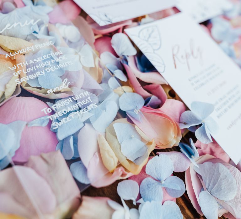 Clear acrylic menu with pastel flower petal confetti and wedding stationery 