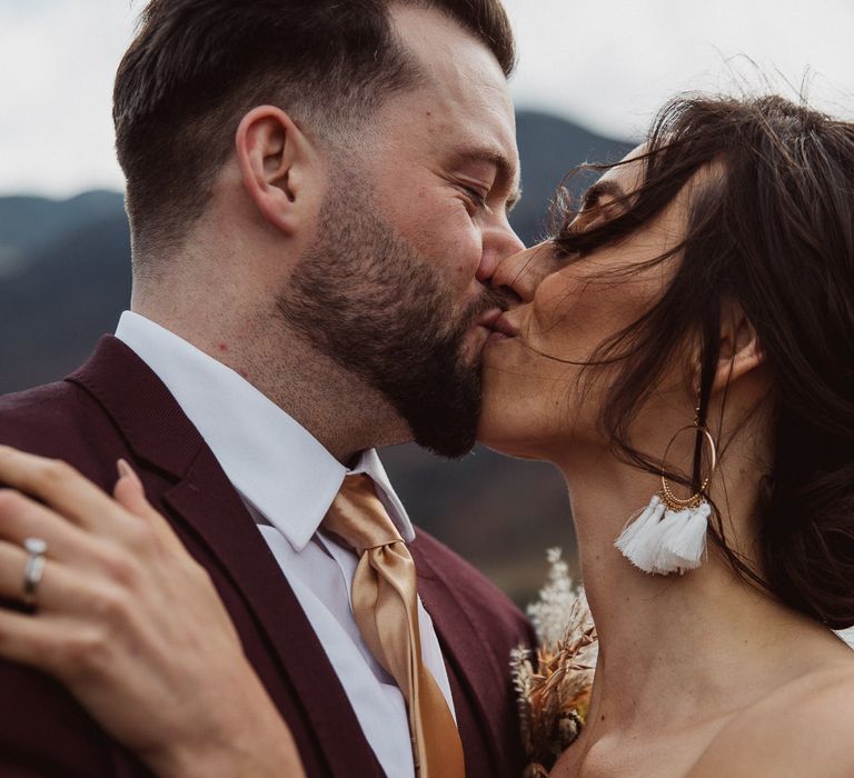 Smiling bride and groom kiss outside at small wedding in the Lake District 