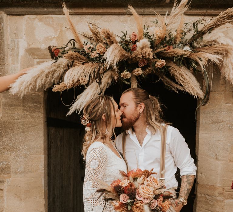 Bride & groom kiss surrounded by floral decoration 