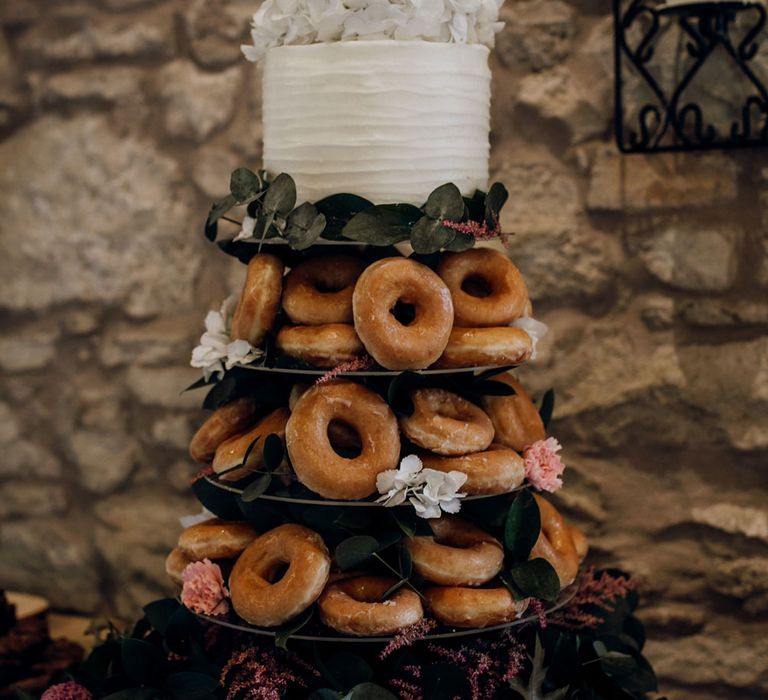 Rustic doughnut wedding cake stack with white one tier wedding cake and floral decorations 