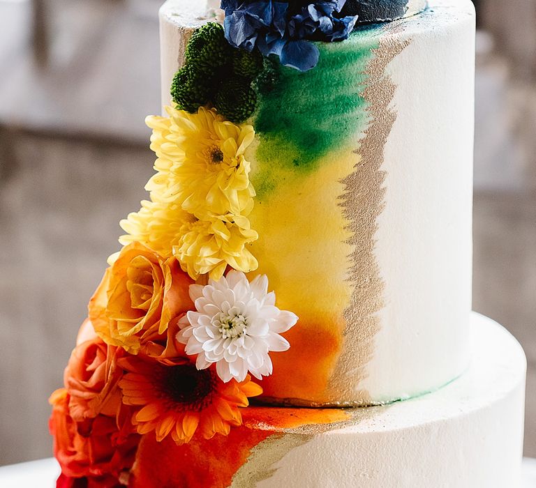 White wedding cake with colourful rainbow design down the front 