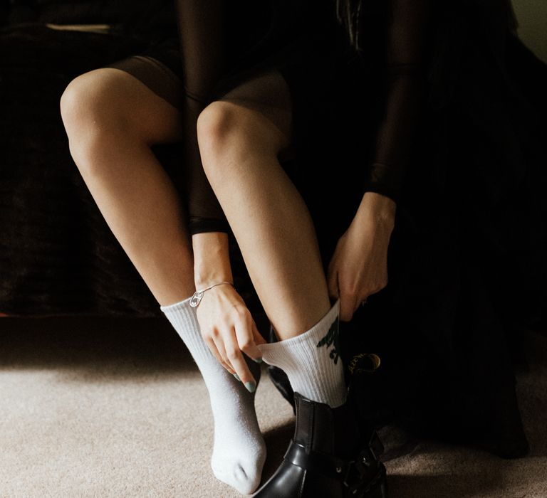 Bride pulls up white socks underneath black Dr. Martens