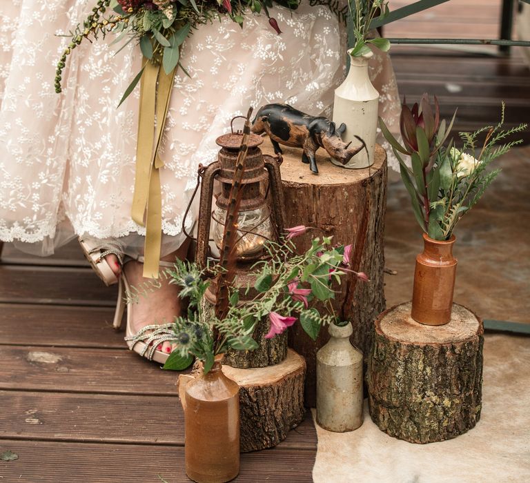 Bride sits at wooden table holding floral bouquet with pink blooms