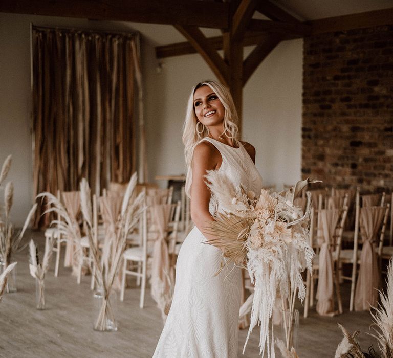 Bride in a fitted wedding dress holding a dried flower bouquet at Pryors Hayes wedding venue 