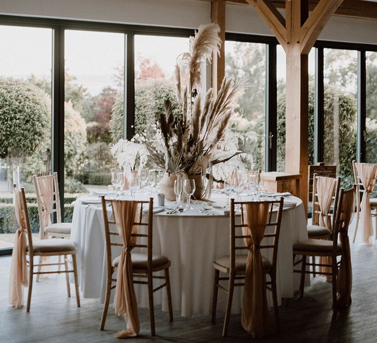 Round reception tables with dried flower centrepieces for rustic barn wedding