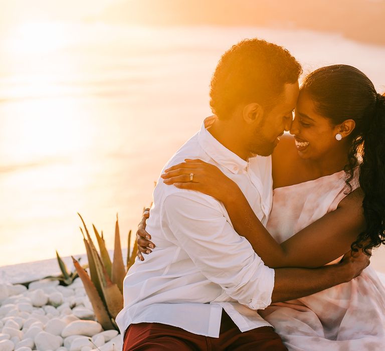 Bride & groom kiss in front of sunset on their honeymoon