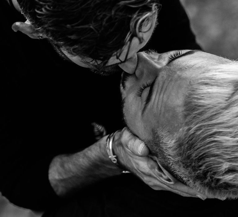 Grooms kiss during their engagement session in black & white image