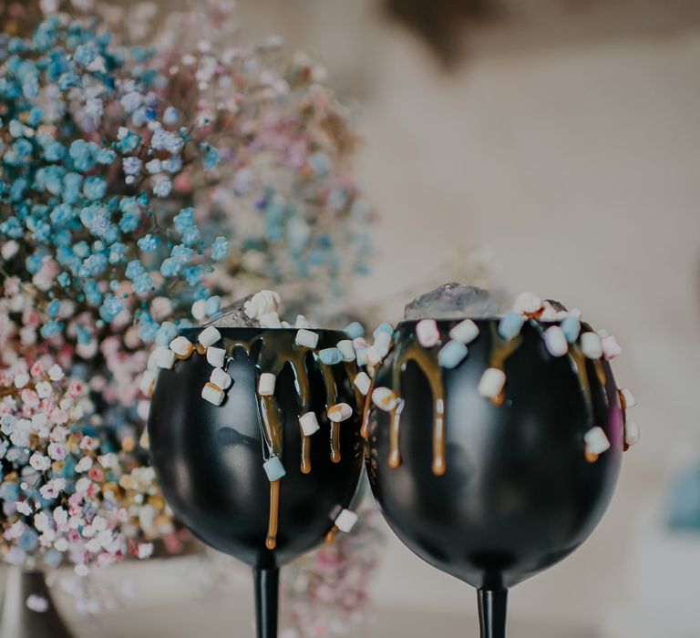 Black goblets topped with marshmallows and dripping sauce sat neck to pastel spray painted gypsophila cloud 