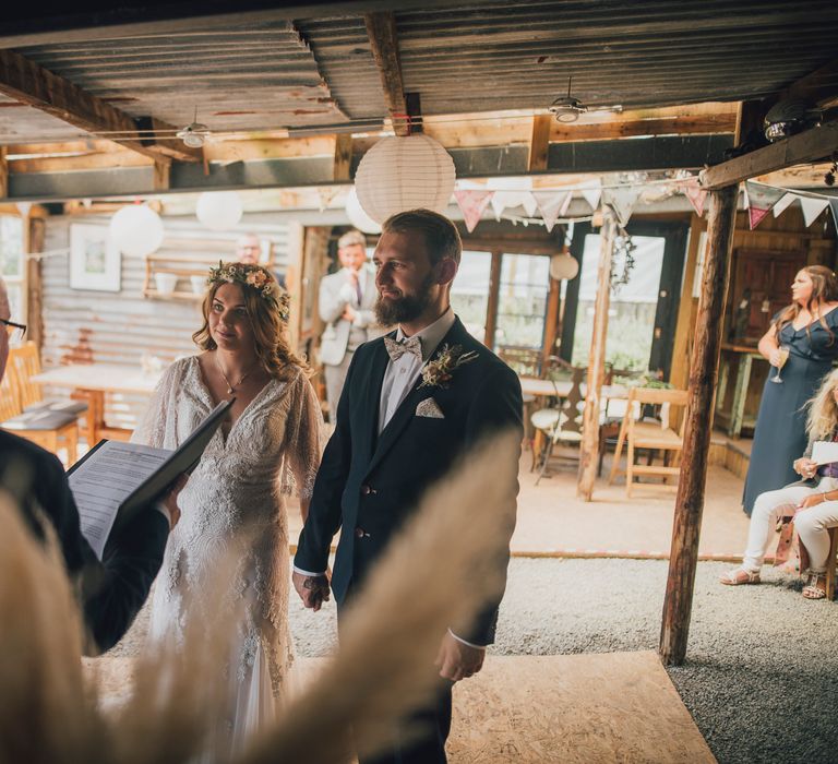 Bride & groom stand together during wedding ceremony at woodland wedding