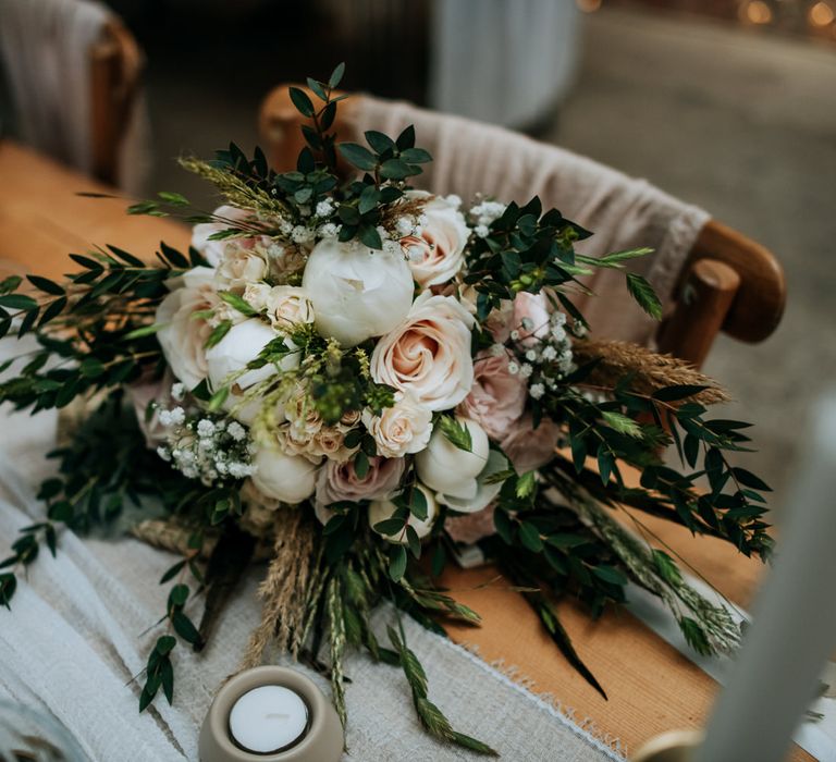 Romantic wedding bouquet with foliage, blush pink roses and white closed peonies 