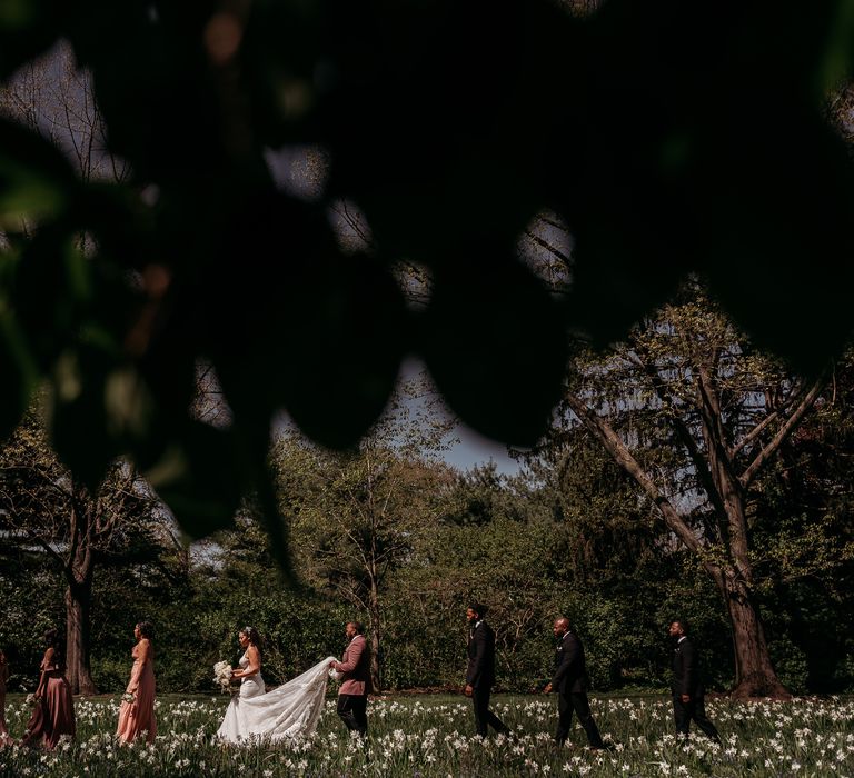 Wedding party walk through gardens together