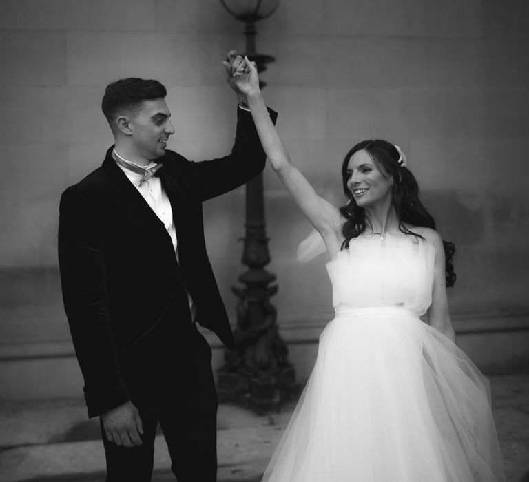 Groom lifts brides arm in the air outdoors after their wedding ceremony in Liverpool